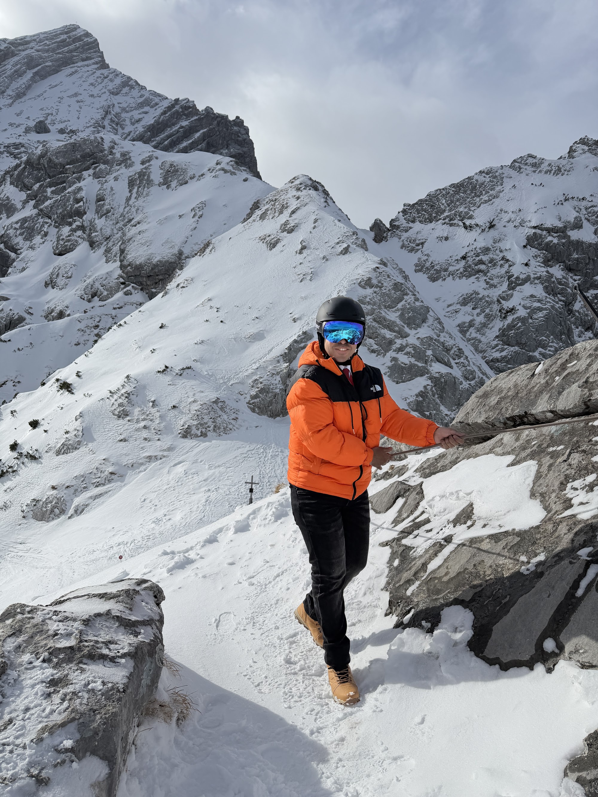 Ahmed in an orange The North Face jacket, helmet and goggles on a snowy mountain in Garmisch-Partenkirchen, February 2026