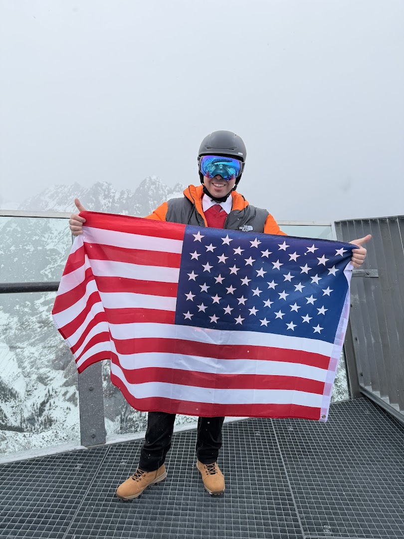 Ahmed holding an American flag on a snowy mountain viewing platform